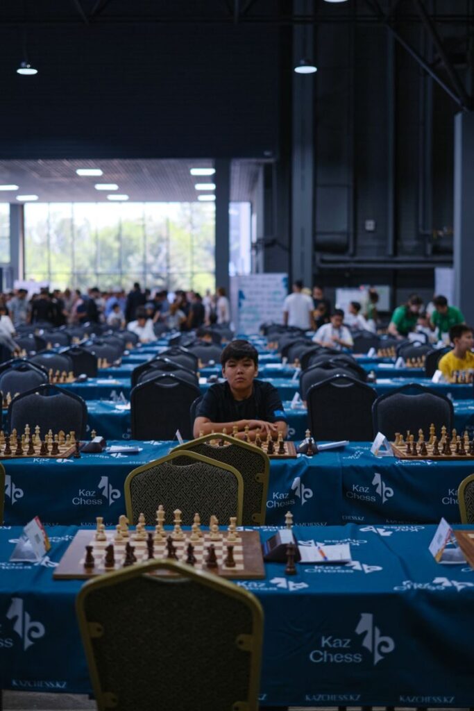 Indoor chess tournament with players, focusing on a young adult participant.